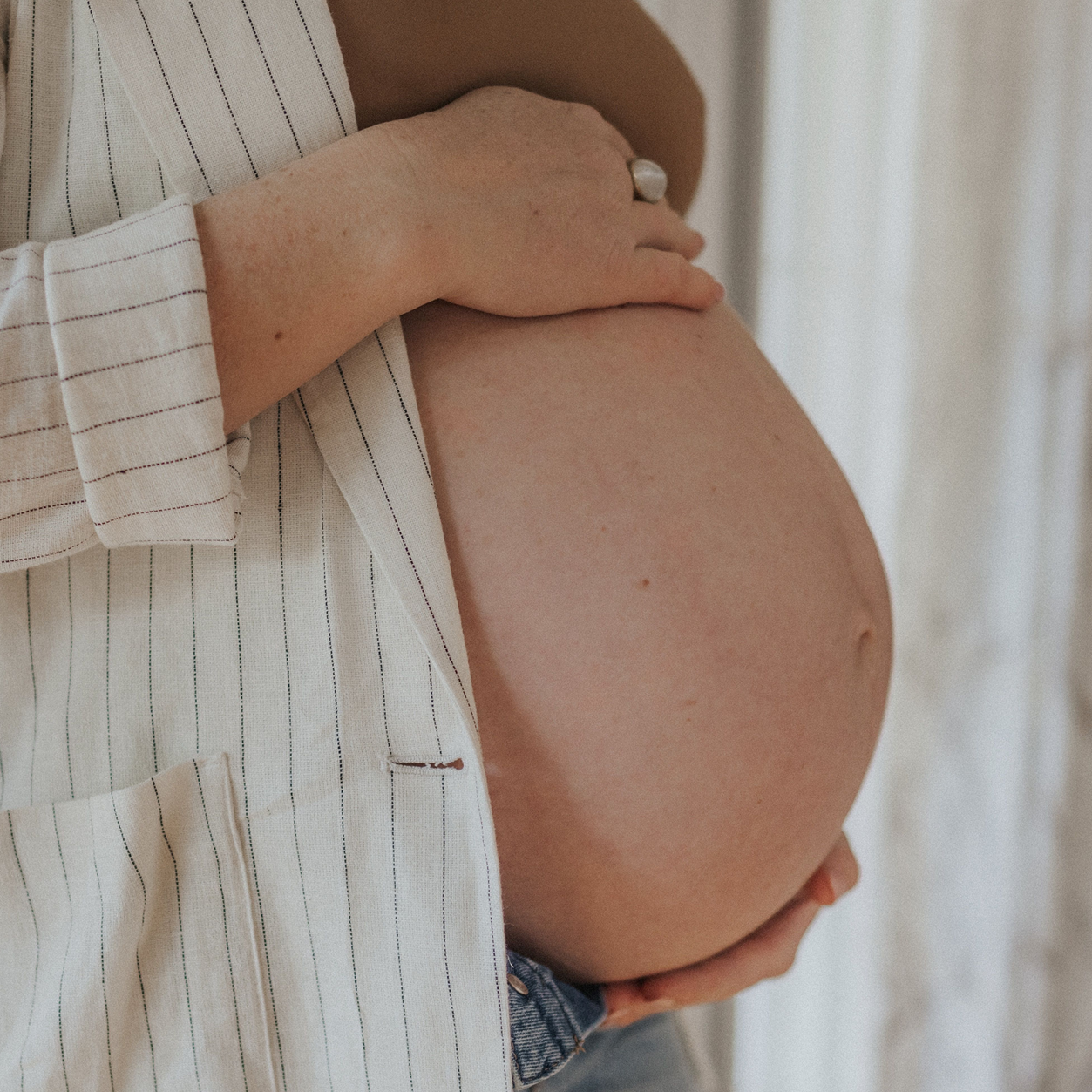 Schwarz-weiß Nahaufnahme eines wachen neugeborenen Babys in einem Schlafsack mit Flugzeug-Motiv, das aufmerksam in die Kamera blickt.